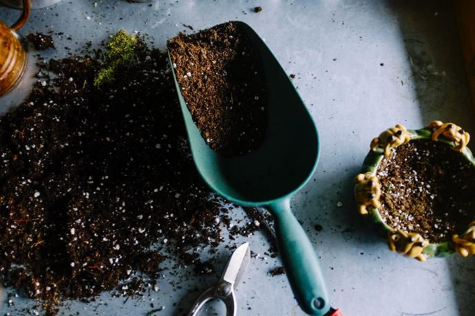 green metal garden shovel filled with brown soil